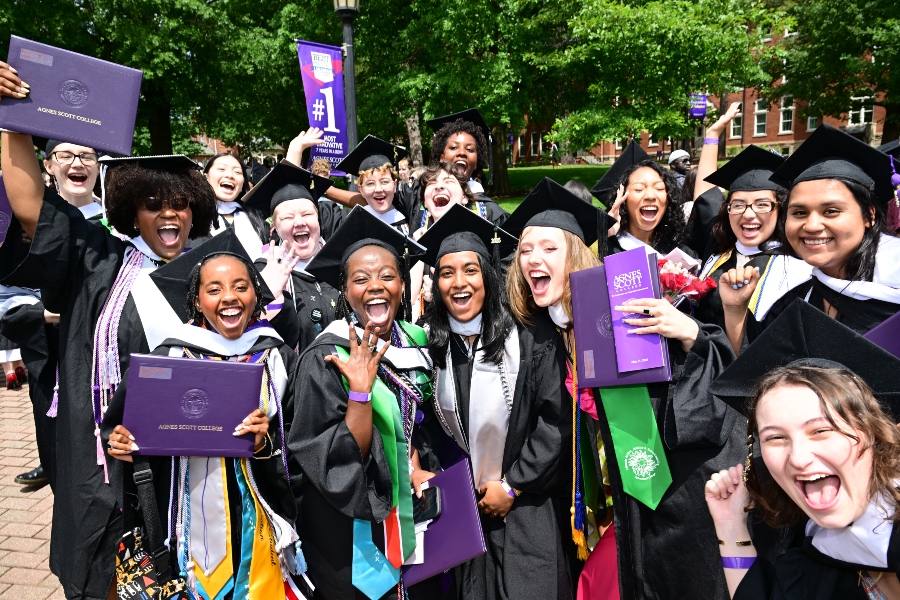 A group of students gather for a photo while holding their purple diplomas