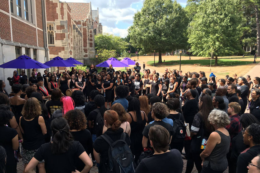 A large group of people wearing black gather outside that Alston Campus Center.