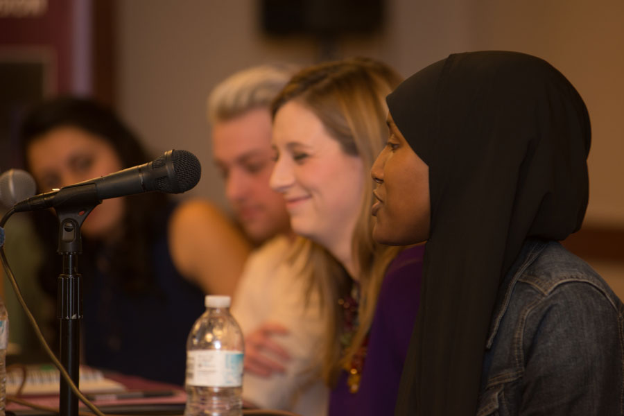 Four panelists discussing human rights and social justice. The person speaking is wearing a hijab.