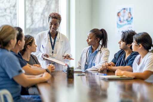 A group of graduate health professions students gathered at a table with a professor leading discussion