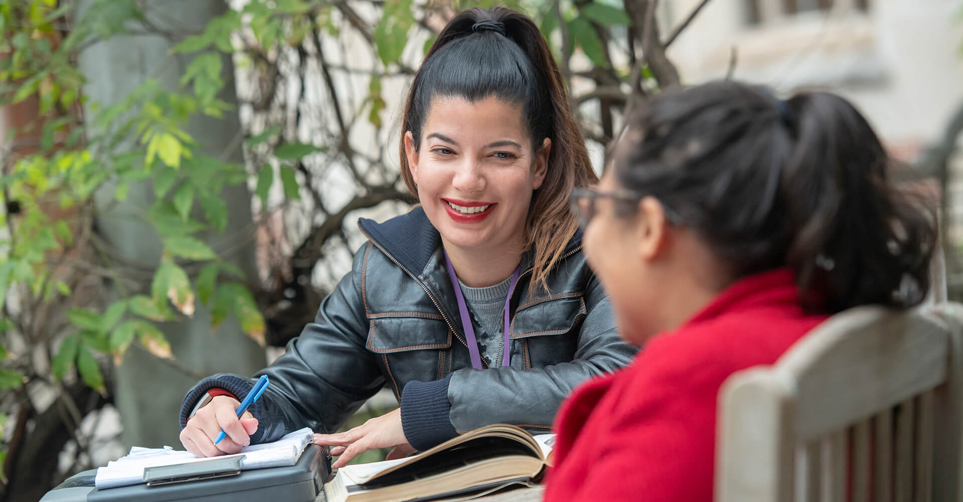 Two students engaged in conversation while studying outside.