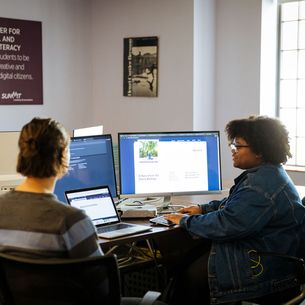 Women and gender studies major students talking and typing on a desktop computer.