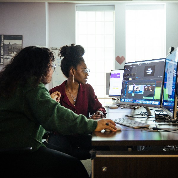 two students sit at a computer editing data