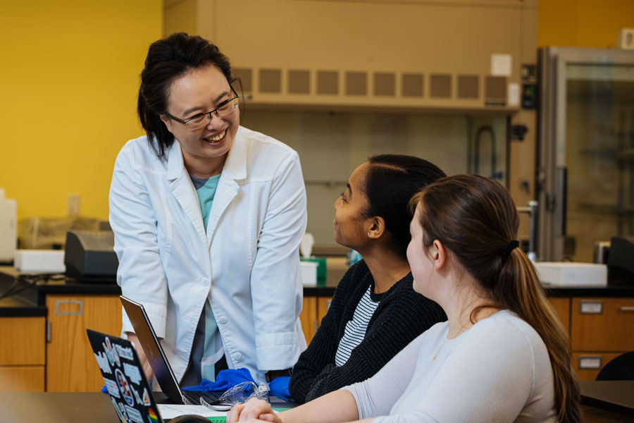 Students asking a professor a question in a science lab