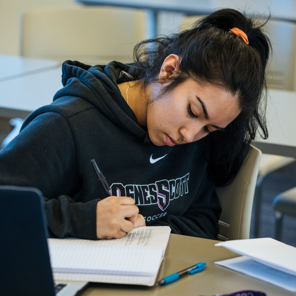 An English literature student take notes during class in her notebook.