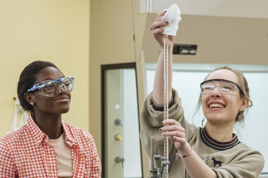 Two Agnes Scott pre-health program students sanitize a piece of medical equipment.