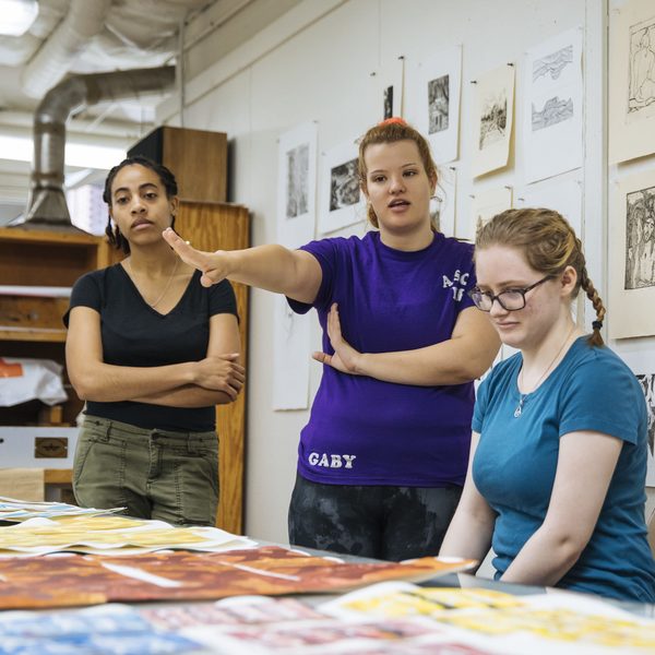 Three Agnes Scott studio art major students observe pieces of art in class.