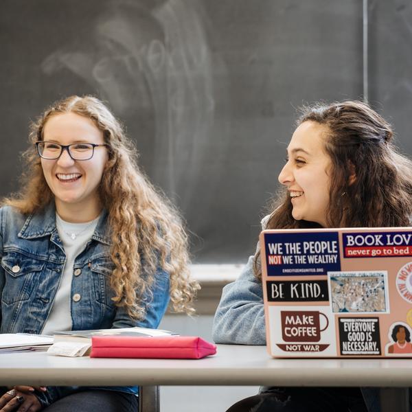 Two math major students smile and laugh as they attend class.