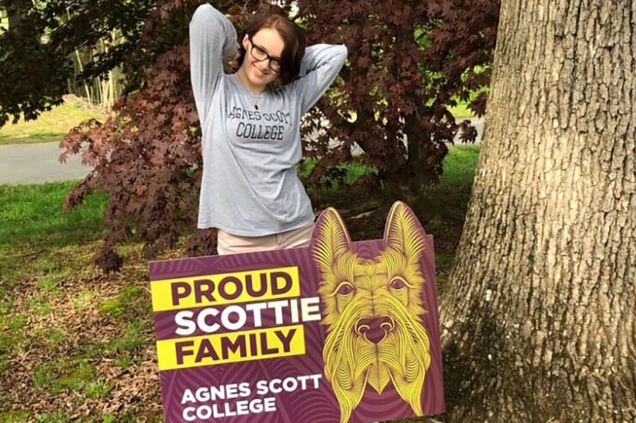 student standing behind Scottie pride yard sign