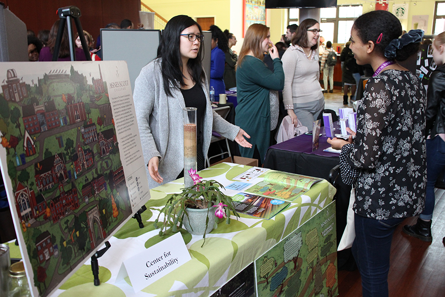 Students talk to staff member standing behind a table