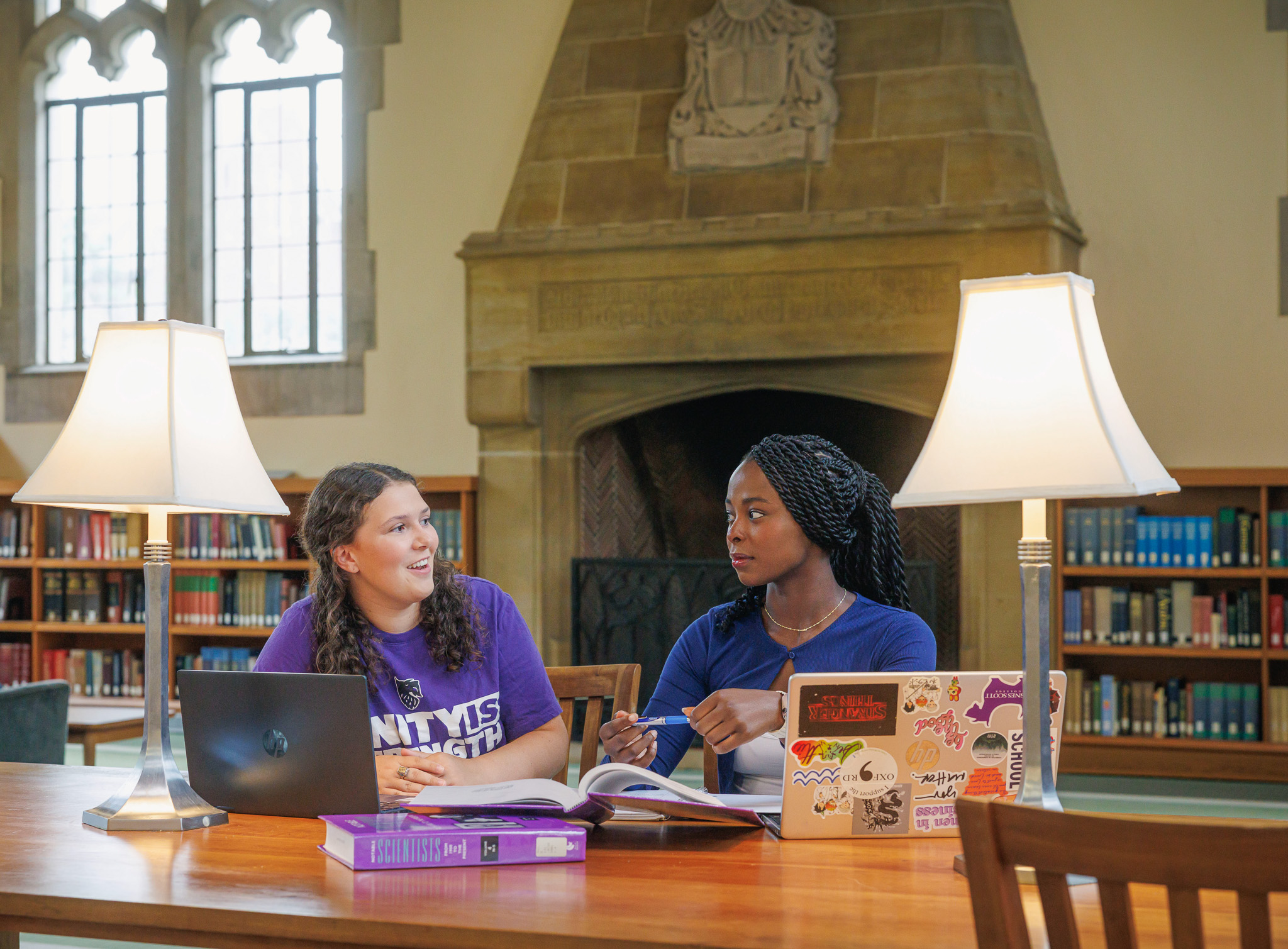 Two Agnes Scott students sitting in the library and talking
