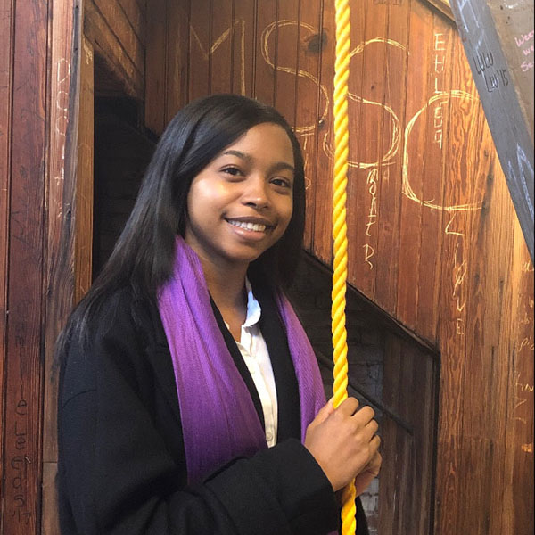 Smiling student holding rope to the bell tower