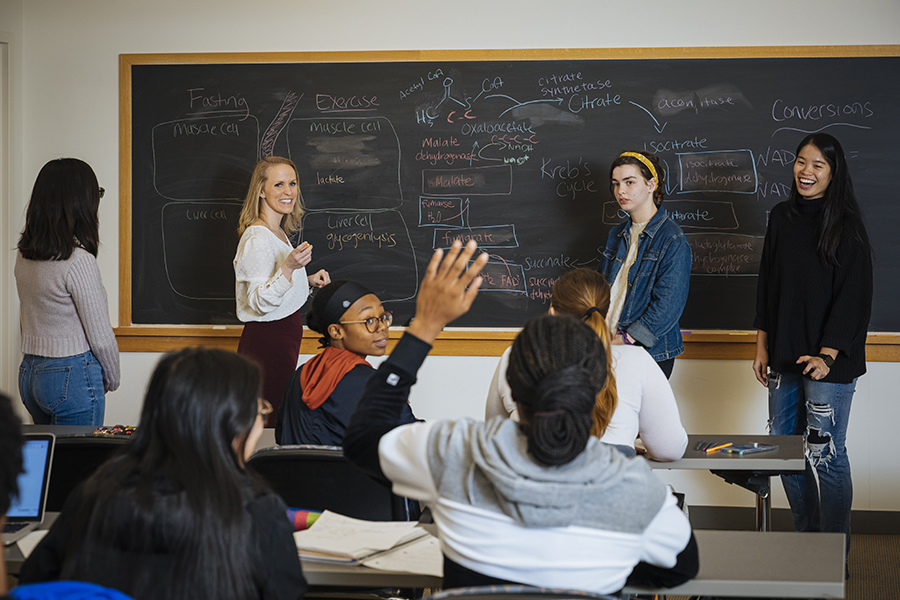 A group of undergraduate students writing on a chalkboard in chemistry class at Agnes Scott, an affordable private college.