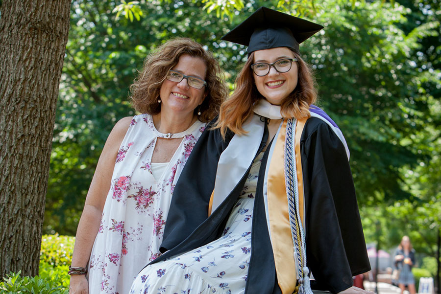 Smiling parent with smiling student in cap and gown