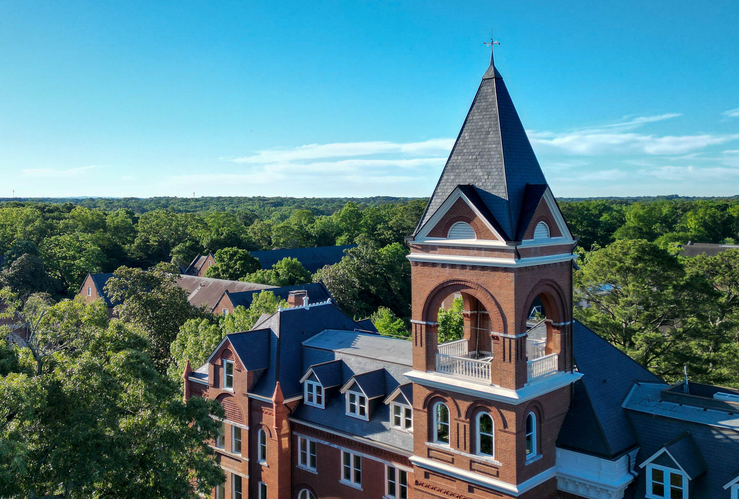 an aerial shot of a red brick tower and building on campus
