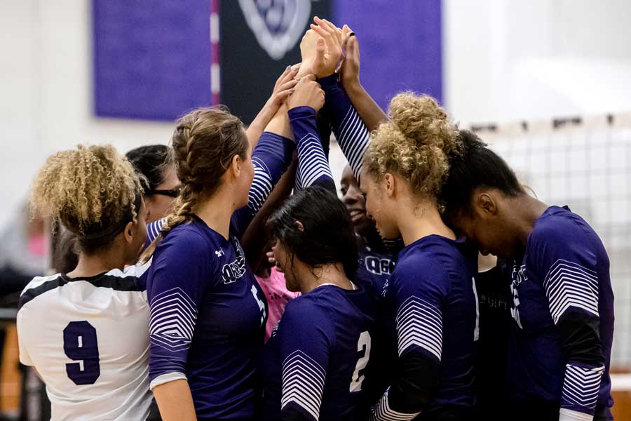 Members of Agnes Scott's soccer team gather with their hands in a circle to kick of the start of game.