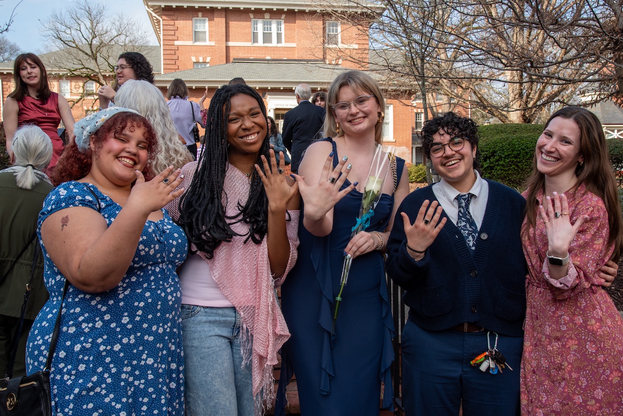 Five Agnes Scott students proudly displaying their class rings on their fingers. 