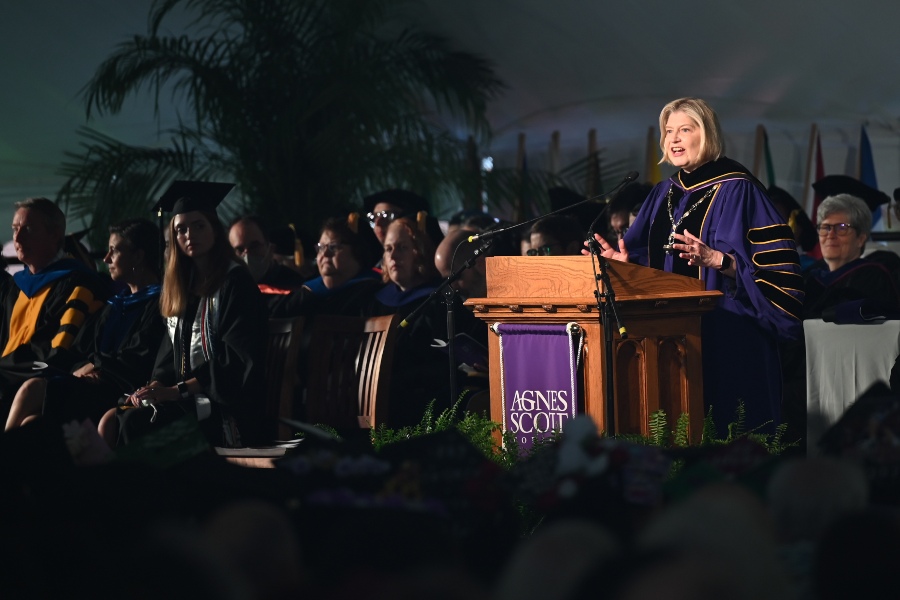 A spotlight focus on a college president in purple and black robe. 