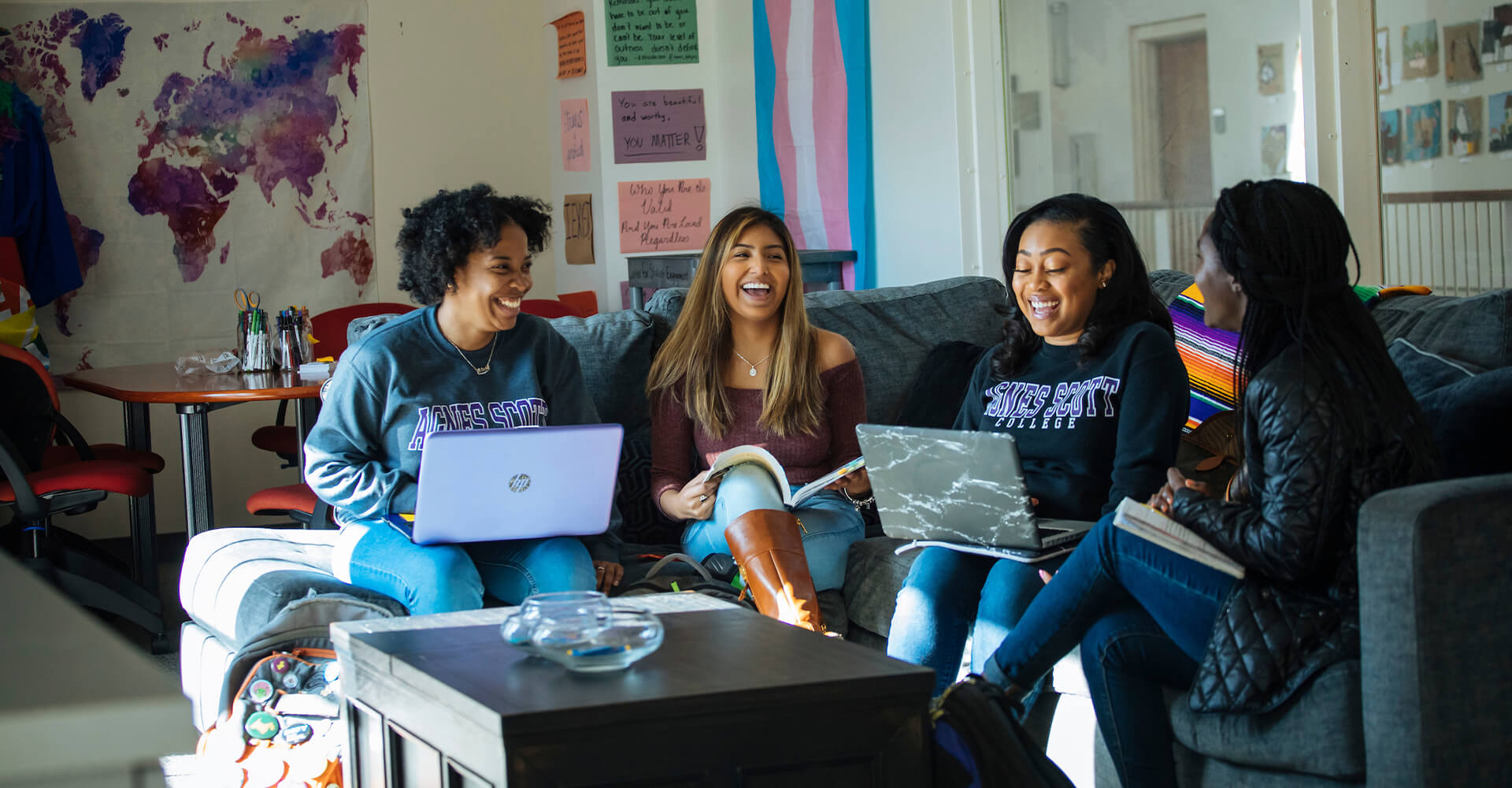 four students on a couch studying and laughing