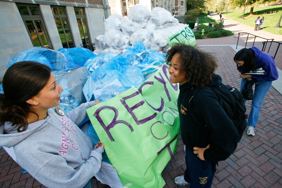 agnes Scott students talking while standing near large bags of recycled items.