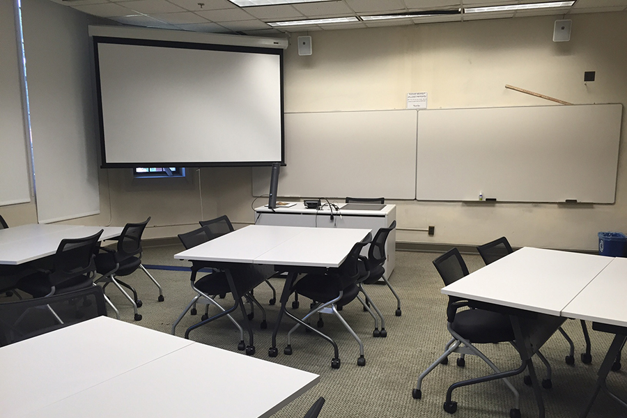 Buttrick classroom with desks, projection screen and whiteboards