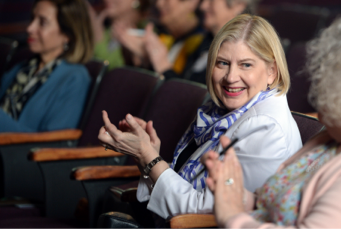 President Zak, sitting in an auditorium seat, applauds