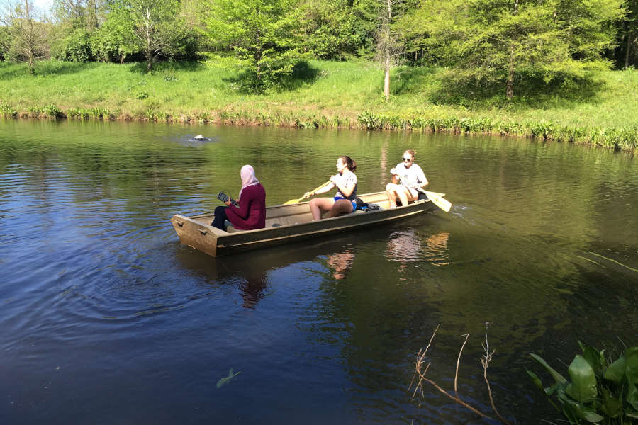 three students in a boat on Lake Agnes