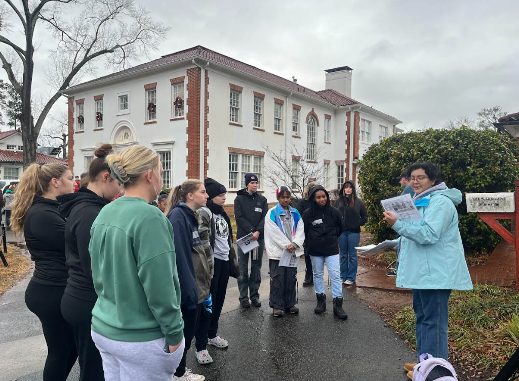 two students stand at local waterway with faculty member learning stream monitoring