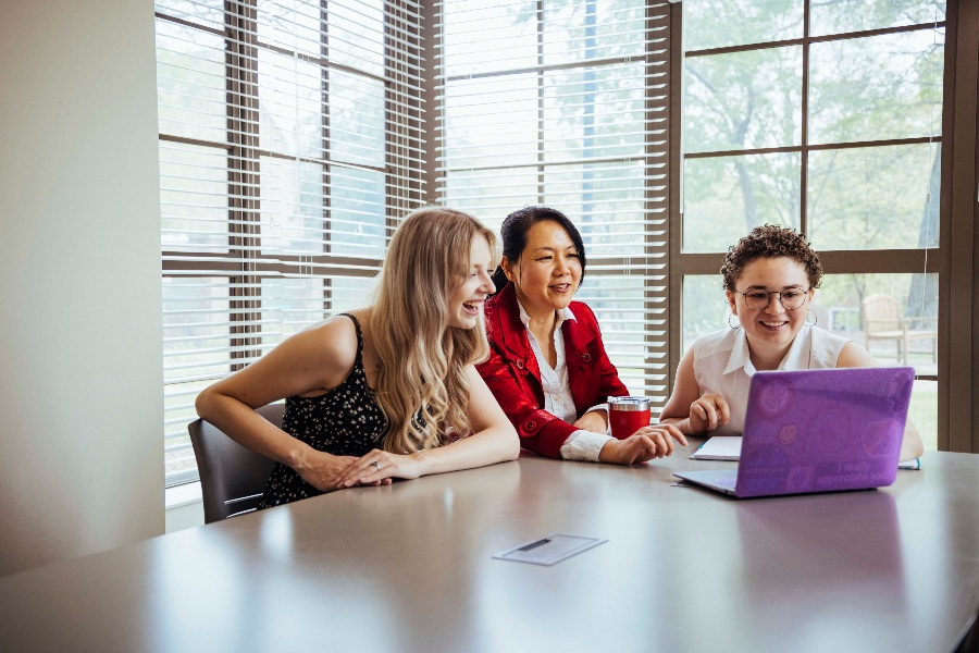 group of people discuss something while looking at computer screen