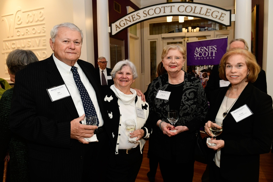 A group of donors stand together in a row with an artistic arch in the background that reads Agnes Scott College