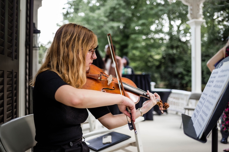 A student plays the violin while looking a sheet music. 