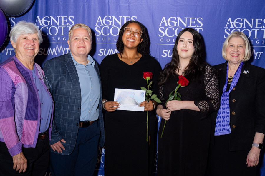 Two Agnes Scott College student award recipients stand with donors and college representatives during the 2026 Student Award Celebration. The students hold award certificates and red roses while posing in front of an Agnes Scott and SUMMIT event backdrop.