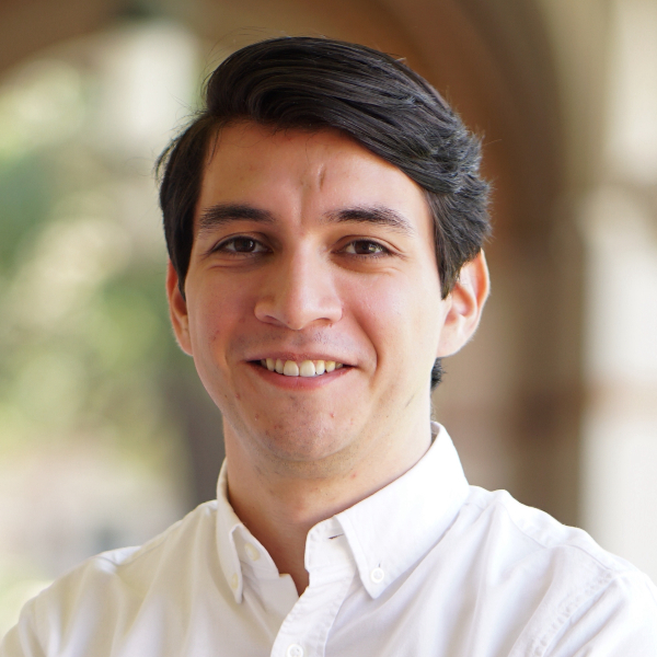 Headshot of Enrique Quezada with a natural background.