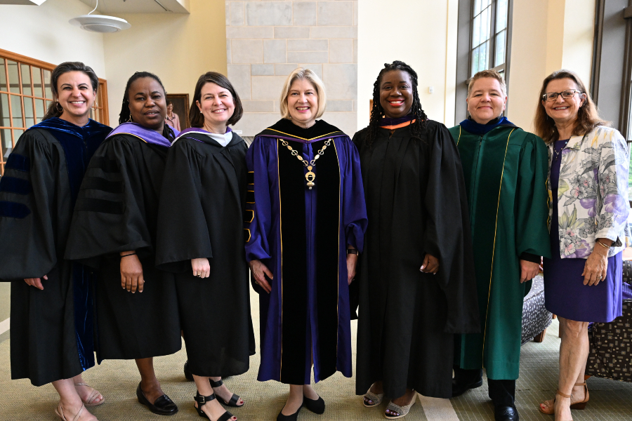 A group of college leaders pose for a photo, dressed in formal regalia