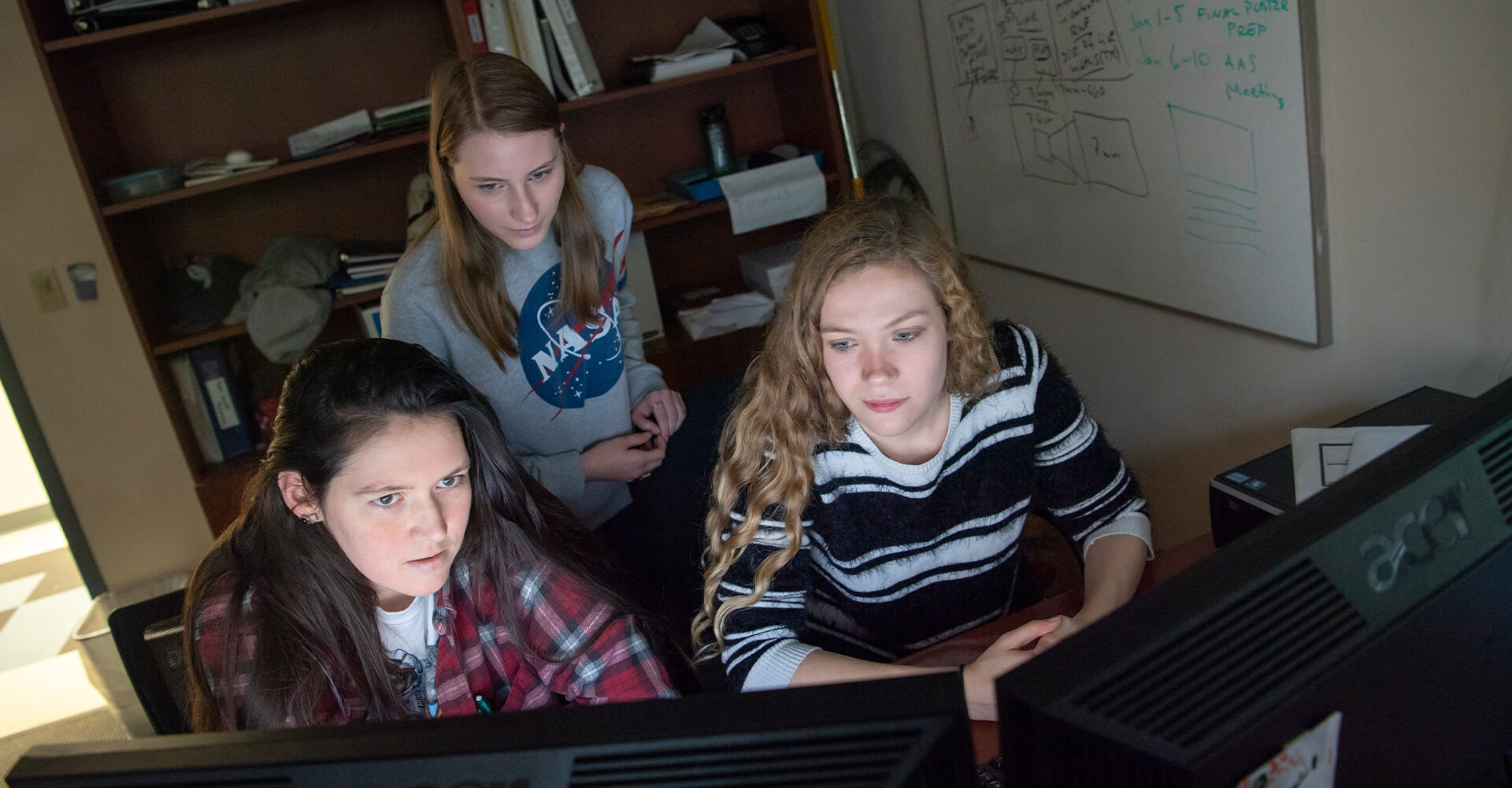 three students working on a computer