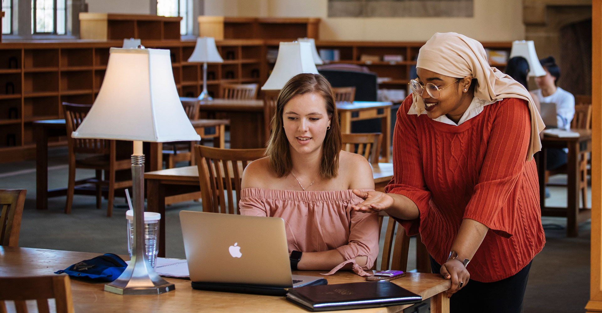 two students looking at a computer in a library